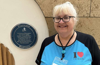 Hev em frente à placa que foi colocada com seu nome em uma escada rolante no shopping Bluewater