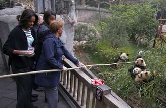 <p>Michelle e as filhas deram pedaços de maçãs fixados na ponta de uma longa vara de bambu aos pandas</p>