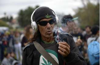 <p>Homem fuma um cigarro de maconha em um parque onde pessoas se reuniram durante a Primeira Marcha Mundial pela Maconha Regulada, em Montevidéu, neste 3 de maio</p>