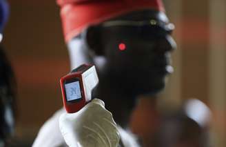 Agente de saúde mede a temperatura de um homem na Nigéria; país tem 14 casos