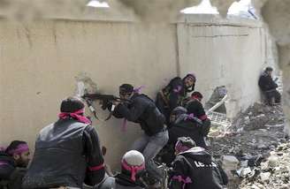 <p>Combatente do Exército Sírio Livre dispara rifle por um buraco na parede de uma base militar síria durante confronto no bairro de Arabeen, em Damasco</p>