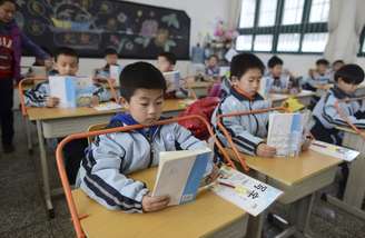 <p>Alunos lêem livros em mesas equipadas com o objetivo de prevenir a miopia, em uma escola primária em Wuhan, província de Hubei, China, em 10 de março</p>