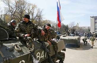 <p>Homens armados sentam sobre um carro blindado, com uma bandeira russa, em Slaviansk, na Ucrânia, nesta quarta-feira; país vive clima instável e ameaça de guerra civil</p>