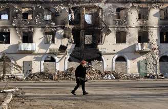 <p>Homem caminha próximo a edifício destruído em cidade ucraniana</p>