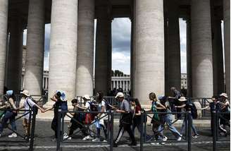 Um grupo de jovens caminha de mãos dadas em frente ao Vaticano após a Santa Missa sobre a Divina Misericórdia, no segundo dia de luto pelo Papa Francisco, em 27 de abril de 2025, em Roma, Itália. Os ritos fúnebres do falecido Papa Francisco são realizados por nove dias após seu sepultamento, enquanto ele é lamentado e celebrado pelos fiéis. Durante esse período, o Vaticano se prepara para o processo de eleição de um novo Papa, conhecido como Conclave, que deve começar de 15 a 20 dias após a morte do Papa.