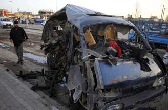 Iraquiano observa veículo destruído após explosão no bairro de Sadr, em Bagdá