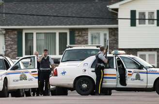 <p>Oficiais se escondem atrás de viatura em Moncton, New Brunswick, Canada, em 4 de junho</p>