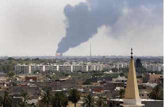<p>Uma coluna de fumaça é vista no horizonte durante um incêndio em um depósito de óleo atingido durante batalhas entre milícias rivais, em Tíipoli, em 28 de julho</p>