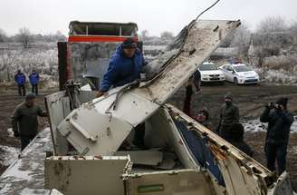 Trabalhadores locais transportam destroços do voo MH17 no local da queda do avião, perto do vilarejo de Hrabove, no leste da Ucrânia, no ano passado. 16/12/2014