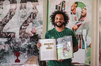 v - Legenda: Felipe Melo, do Fluminense, com o livro sobre a conquista inédita da Libertadores