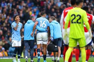 Carl Recine/Getty Images - Legenda: Rodri deixa o campo com ajuda de médicos do City