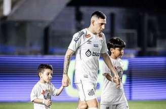 Divulgação/ Santos FC - Legenda: Jogador do Santos entrando com crianças em campo