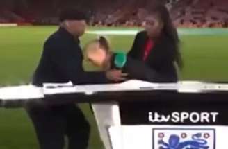 - Reprodução de Vídeo - Legenda: Laura Woods, apresentadora da ITV, passa mal antes de Inglaterra x Gana, de futebol feminino, e é amparada por Ian Wright