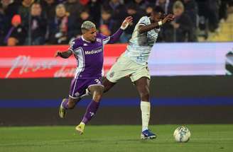 Yann Bisseck da Inter (de branco, à esquerda), e Robin Gosens da Fiorentina correm para tentar dominar a bola.