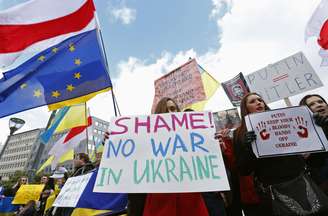 Pessoas acompanham, do lado de fora, uma reunião de emergência dos ministros do exterior da União Europeia, em Bruxelas, protestando contra a presença das tropas russas na Ucrânia, em 3 de março