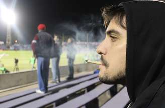 Estudante Diego Pazos, 23 anos, fuma calmamente um cigarro de maconha durante o intervalo de Danubio x São Paulo