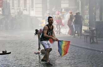 Participante de Parada Gay na Turquia reage enquanto outros fogem após a polícia ter usado canhões de água para dispersar o público