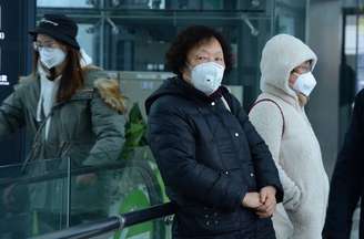 Mulheres se protegem com máscaras em estação ferroviária em Xangai, na China