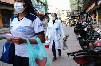 Agente comunitária de saúde e enfermeira caminham na Rocinha, no Rio, durante a pandemia de covid-19