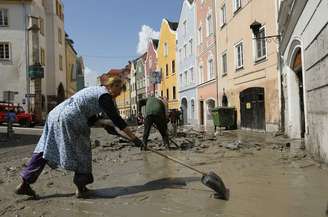 Moradores removem a lama da frente de suas casas em Schaerding, na fronteira da Áustria com a Alemanha