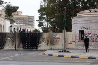 Homem passa em frente ao Congresso da Líbia, atacado por manifestantes neste domingo