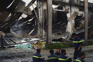 <p>Bombeiros descansam perto de uma fábrica de sapatos chinesa que foi danificada, no sul da província de Binh Duong, no Vietnã, em 14 de maio</p>