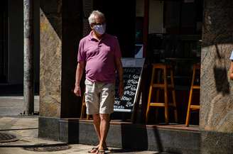 Pedestres são vistos usando máscara de proteção facial pelas ruas do bairro de Botafogo, na zona sul do Rio de Janeiro