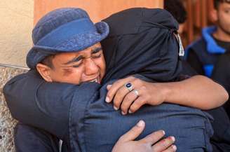 Pessoas em luto se abraçam durante o funeral de palestinos que, segundo médicos, foram mortos em um ataque israelense no domingo, no Hospital Nasser em Khan Younis, sul da Faixa de Gaza 
11 de janeiro de 2026
REUTERS/Haseeb Alwazeer