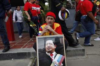 <p><strong>15 de março - </strong>Com foto de Chávez, seguidor aguarda para despedida final do falecido presidente</p>