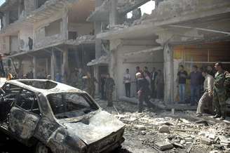 Pessoas se aproximam de local onde dois carros bombas explodiram nesta terça-feira em Homs