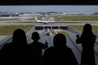 <p>Pessoas olham para fora de uma janela enquanto um Boeing da Malaysia Airlines taxia no Aeroporto Internacional de Kuala Lumpur, na Malásia, em 14 de junho</p>