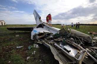 <p>Pessoas sobem e tiram foto em meio aos destroços de um AN-26, avião de transporte militar ucraniano, que foi derrubado por um míssil, na aldeia de Davydo-Mykilske, leste de Lugansk, perto da fronteira russa, na última segunda-feira, 14 de julho</p>