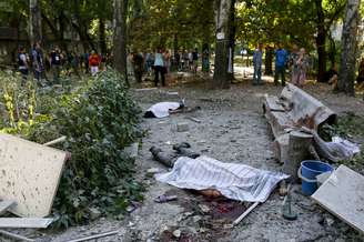 <p>Moradores e jornalistas observam os corpos das vítimas de um recente bombardeio realizado pelas forças de segurança da Ucrânia em Donetsk em 23 de agosto</p>