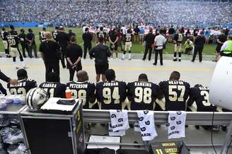 Jogadores do New Orleans Saints sentados durante o hino nacional