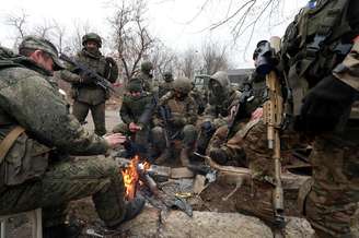 Membros do serviço de tropas pró-Rússia em uniformes sem insígnias se reúnem em torno de uma fogueira no assentamento controlado pelos separatistas de Mykolaivka (Nikolaevka), enquanto a Rússia continua ofensiva contra a Ucrânia