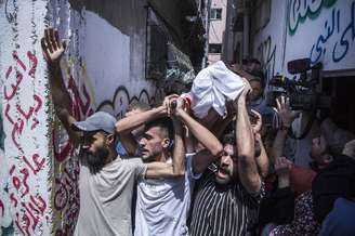 Palestinos carregam corpo de vítima de bombardeios israelenses em Gaza
