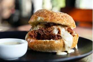 Sanduíche de costela bovina cozida na cerveja da casa coberta com creme de fondue do restaurante Cão Véio, do chef Henrique Fogaça