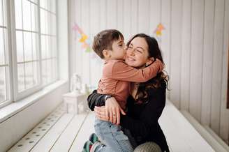 Mãe e filho pequeno se abraçando em casa.