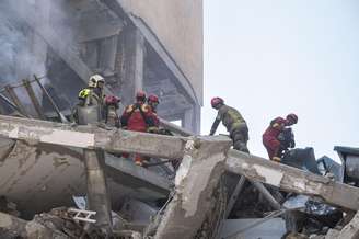 Bombeiros iranianos trabalham no local de um prédio residencial destruído devido aos ataques israelenses em Teerã, Irã, em 13 de junho de 2025.
