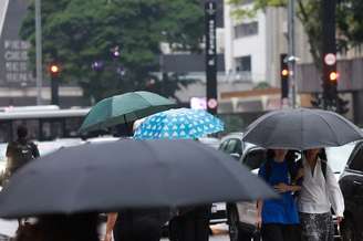 Pedestres caminham com guarda-chuva na Av. Paulista
