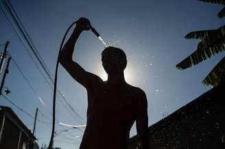Um homem se refresca com uma mangueira na rua em meio a uma onda de calor no Rio de Janeiro em fevereiro de 2025