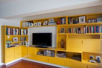 A arquiteta Claudia Pecego criou uma sala de TV onde antes ficava a garagem da casa. O grande móvel amarelo foi desenhado pela profissional para combinar com o piso original de cerâmica vermelha. Informações: (11) 3444-4877