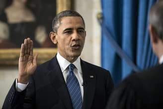 Obama levanta o braço direito e faz o juramento diante do juiz John Roberts, presidente da Suprema Corte