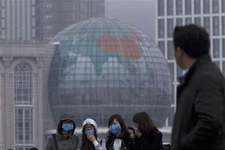 Mulheres vestindo máscaras caminham ao longo do rio Huangpu, no centro de Xangai. A Organização Mundial da Saúde (OMS) disse que não há sinais de "transmissão sustentada humano a humano" do vírus H7N9 na China, mas que é importante acompanhar 400 pessoas que estiveram em contato próximo com os 14 casos confirmados da nova cepa da gripe aviária. 05/04/2013