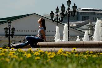 <p>Jovem relaxa na Praça Manezhnaya, em Moscou, onde a tenperatura passou doa 28°C nesta terça</p>