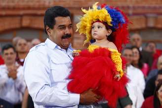 Nicolás Maduro segura criança durante cerimônia para comemorar o 59º aniversário de nascimento de Chávez, em Caracas