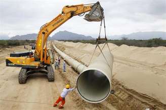 Trabalhador ajuda a colocar parte de um duto durante construção de projeto de irrigação no norte do Peru