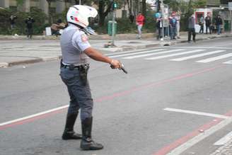 Policial atira para o chão após ser cercado por grupo de manifestantes, em São Paulo