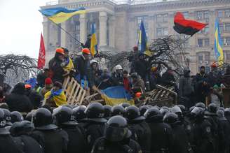 Manifestantes comemoram enquanto a polícia anti-distúrbios deixa a Praça da Independência, no centro de Kiev