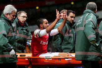 Theo Walcott provoca torcedores do Tottenham enquanto sai de maca; jogador do Arsenal lesionou o joelho e ficará seis meses longe dos gramados
